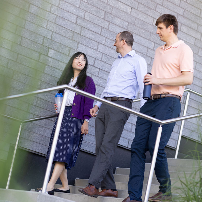 Three staff members talking and walking down the stairs of UBC Okanagan's Commons building.